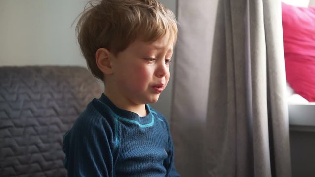 Upset little boy hugging his mother at home