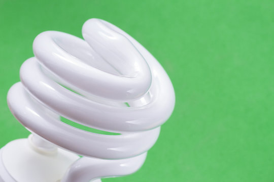 Fluorescent light bulb on green background, technology that contains polluting gases