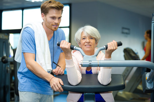 female senior exercising with support of his personal trainer