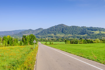 Pictorial field and an asphalt road on the background of mountain peaks, Bled, Slovenia.