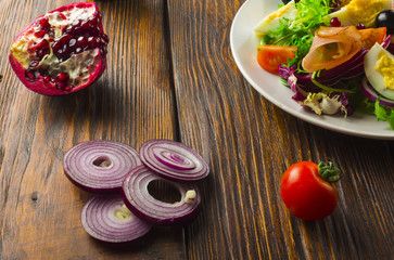Fresh salad with mixed greens and cherry tomato in bowl on wooden background