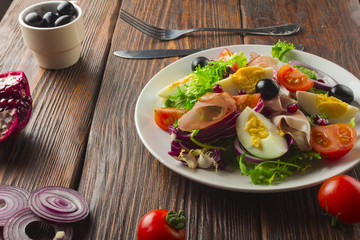 Fresh salad with mixed greens and cherry tomato in bowl on wooden background