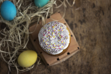 Easter cake and colourful Easter eggs on a wooden table in a wicker box, a religious holiday