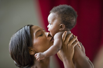Mother holding and kissing her newborn baby