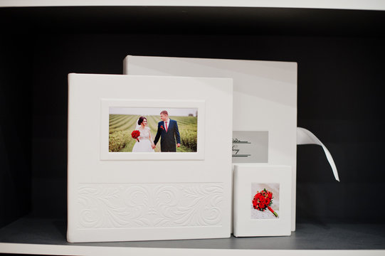 Elegant white or beige photobook, photoalbum and a flash drive case on black background.