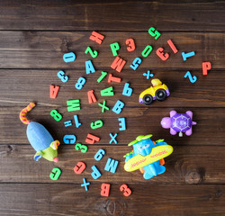 boys toys and colord letters on wooden table. top view.