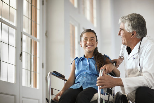 Young girl in a wheelchair talking to her doctor.