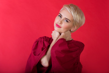 smiling beautiful young girl with short hairstyle on red background