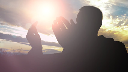 Silhouette of young muslim man praying during sunset
