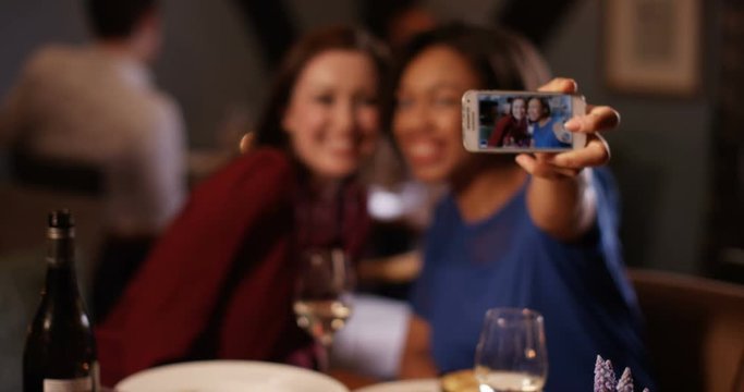 4K Happy female friends enjoying evening out pose to take a selfie with camera phone. Slow motion.