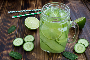 Detox water  with cucumber and lime on the brown wooden background