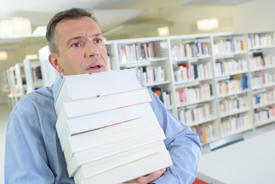 businessman struggling holding many books wish to be promoted
