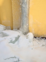 Gutter in the ice against a yellow wall