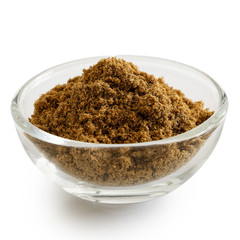 Ground cumin in glass bowl isolated on white.