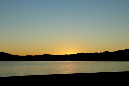 Sunset dips just below the ridge line on the other side of the lake