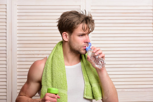 Man with bottle of water, dumbbell and green towel