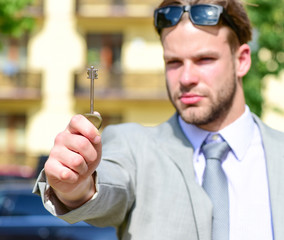 Estate agent holds key to house. Young man in yard