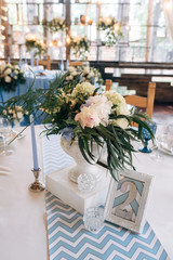 Fototapeta na wymiar Bouquet with fern, eucalyptus and peonies on the table, blue candles and table's number near