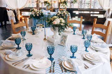 Wedding table decorated in aqua blue color, flowers in antique vase on the centre