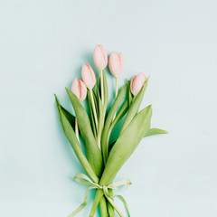 Pink tulip flowers bouquet on pale blue background. Flat lay, top view. Spring floral concept.