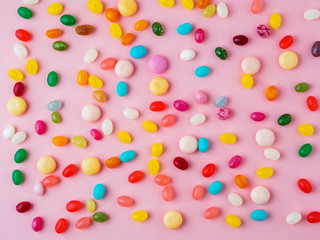 Many scattered colorful sweets, candies, lollipops on  bright pink background, top view