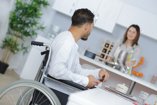 Man in wheelchair talking to partner who is preparing meal