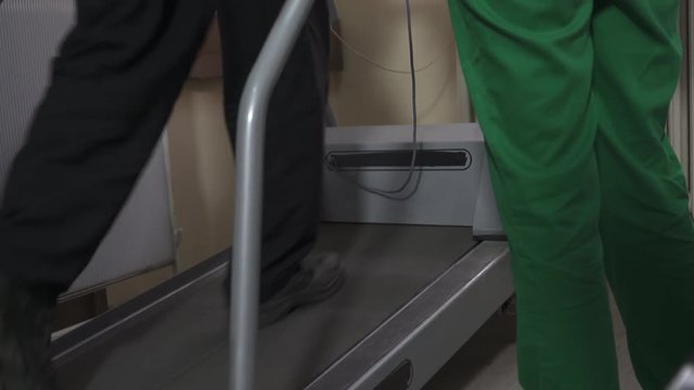 Man Walk On Treadmill, Legs Steps Close Up, Tilt Up. Test For Workload Of Heart,nurse Supervises Male Patient During Cardiology Examination,female Doctor Cardiologist Performing Stress Test For Heart