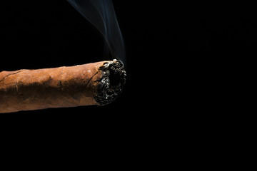 Cigar burnt with smoke on the tip on a black background