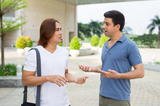 Two Serious Young Men Talking Outdoors