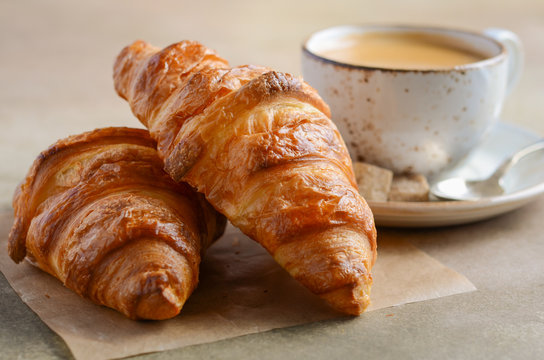 Cup of fresh coffee with croissant on concrete background, selective focus