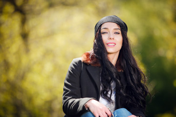 Взрослая красивая женщина сидит на газоне в парке