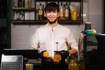 Smiling happy barista giving tea made from sea buckthorn berries healthy for health delicious, saturated with vitamins surrounded by berries in coffee shop.