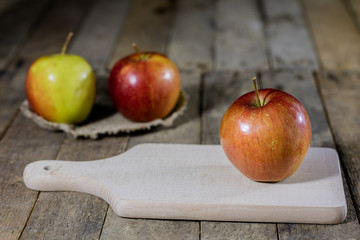 Big red apples in a dark wooden box. Wooden crate and apples on a wooden table in the kitchen.