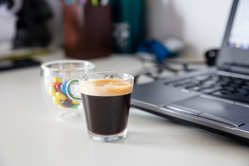 Cup of coffee and cup of colored chocolate filled sweets next to