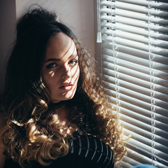 Woman with long hair stand at window shutters