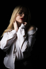 Lovely woman in glasses wearing blouse with naked shoulders, posing with dramatic studio light