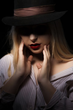 Sensual blonde woman wearing white blouse and hat, posing with shadow on her face