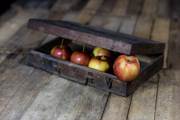 Big red apples in a dark wooden box. Wooden crate and apples on a wooden table in the kitchen.