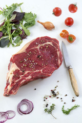 Raw T-bone Steak for grill or BBQ on cutting board with knife over on a white background, top view