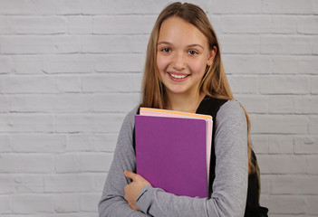 Portrait of happy smiling school teen age girl wearing backpack and books.