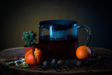 hot tea in a teapot on a wooden board with mandarins and cactus