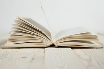 Open of pastel colorsbooks hardback on wooden table.