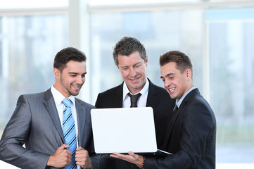 business partners with a laptop standing in the lobby of the office.