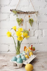 Easter, painted eggs in a container, a bouquet of yellow daffodils.
