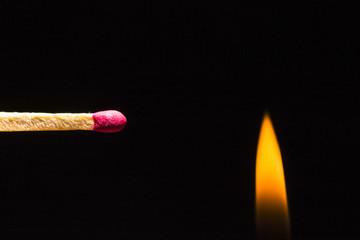 Match stick with fire on the right side of the frame on a black background
