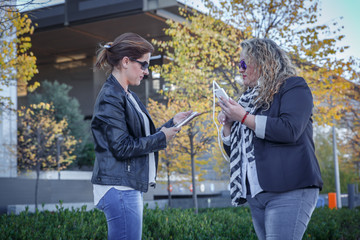 Two mature women check their mobile phones