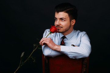 Handsome romantic happy man in casual holding and smelling rose and looking away.