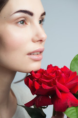 Beauty Fashion Model Woman face. Portrait with Red Rose flowers. Perfect skin.