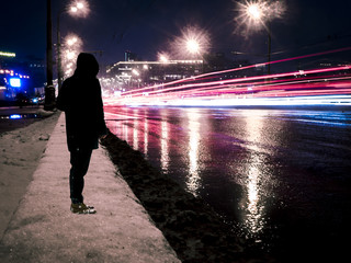 young man standing near the traffic on the highway, long exposure shot