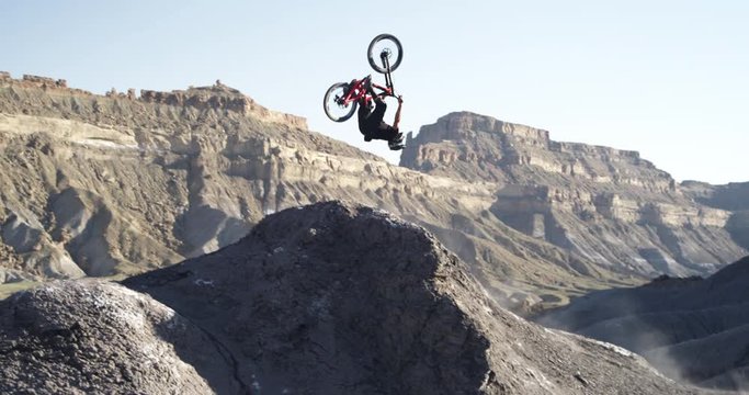 Slow motion, mountain biker does backflip off jump in Utah canyon